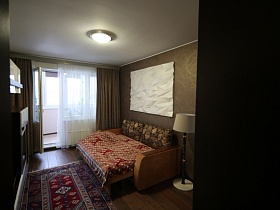 цветной коврик на полу между мебельной стенкой и разложенным диваном в спальной комнате с дизайнерским ремонтом современной трехкомнатной квартиры