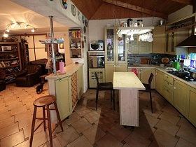 зона кухни с бежевой мебелью,барным столом и барной стойкой в просторной комнате классической семейной дачи