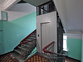 чистый ухоженный подъезд с белым потолком и бирюзовыми панелями на стенах, лестничными пролетами и квадратной плиткой на полу этажа жилого сталинского дома для съемок кино