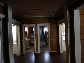 открытые двери в санкомнаты в холле деревянного съемного современного коттежда