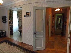 открытый дверной проем на кухню и открытая дверь в прихожую из светлой гостиной с большим ковром на полу кв 27