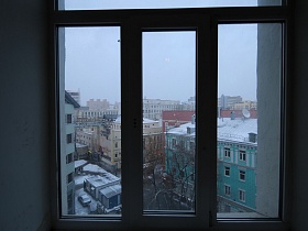 вид из окна лестничной площадки светлого подъезда жилого дома на придомовую территорию и соседние дома на Новослободской