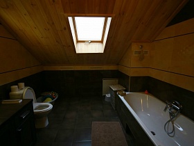 свет от большого окна в потолке ванной комнаты в мансарде уютного современного загородного дома-избы
