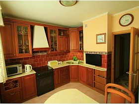 коричневая кухня с бежевой рабочей поверхностью и плиткой под кирпич в современной кухне приличной трехкомнатной квартиры
