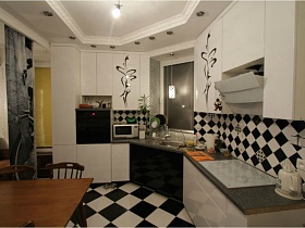белая с черным мебель гармонично сочетается с цветом стен, и пола в кухне квартиры с выходом на крышу магазина