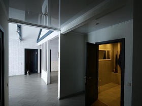 прямоугольное зеркало в белой рамке на стене ванной комнаты и полотенца на стене ванной комнаты из открытой двери просторной светлой прихожей скандинавской дачи