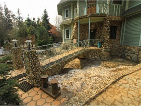 сказочный дворик интересного дома с бассейном, выложенным диким камнем и мостиком с резными перилами