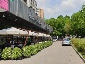 уютные столики на отдельной площадке под белыми зонтиками за зеленым оградением при ресторане Академия