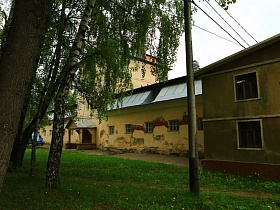длинное желтое здание с башней посередине, маленькими окнами в стенах, требующих ремонта в старом городке