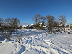 расчищенная от снега дорога в деревне у пруда