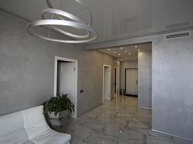 серые стены и потолок, серая плитка под мрамор на полу гостиной ведущие в прихожую с белой входной дверью