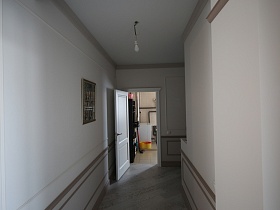 лампочка на белом потолке, картина на стене с отделочными панелями длинного коридора современного загородного дома
