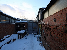 заснеженный двор с большими металлическими воротами музыкального магазина в отдельном кирпичном зданиии
