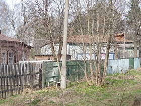 штакетный забор, окрашенный в разные цвета индивидуальных дворов многоквартирного барачного дома в Акуловке на торфоразработках