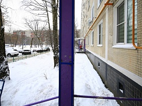 крыльцо подъезда с фиолетовыми колонами и перилами в многоэтажном жилом доме