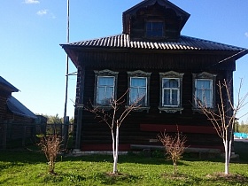резной декор оконных наличников, карнизов на крыше и чердачного окна жилого деревянного дома в старой российской деревне