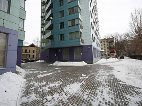 расчищенная плитка от снега на подъездных дорогах к современным башням мегаполиса с жилыми квартирами