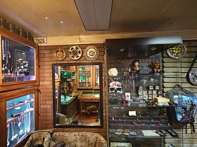 ювелирные украшения под стеклом в шкафу, диски на колеса, сувениры и ленточки с медалями на полочках небольшого магазина мотошмоток