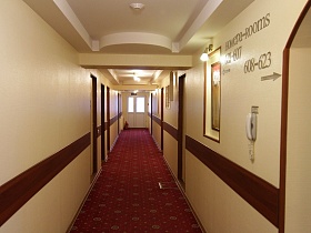 указатель номеров гостиницы в коридоре с вишневым ковровым покрытием на полу
