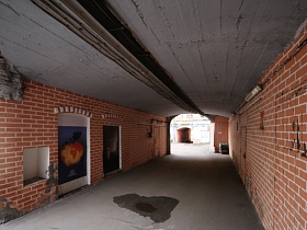 украшенные плакатами двери на стенах арочного проема, выложенных красным кирпичом между домами жилого двора