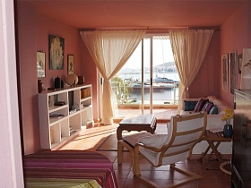 уютный номер отеля Marina Botafoch, картины на стенах, стеллажи с книгами, кресло-качалка