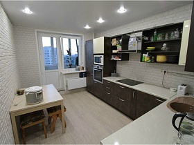 хлебопечка на белом квадратном столе кухни с белыми стенами под кирпич в двухкомнатной квартире новостроя
