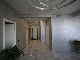 белые двери в разные комнаты из просторной прихожей с большим шкафом-купе у серой стены, переходящей в гостиную