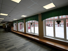 сплошная длинная скамейка у окон в коридоре красивой современной  школы
