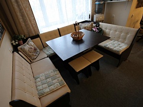 мягкие бежевые угловые диванчики с трех сторон раскладного квадратного стола на кухне