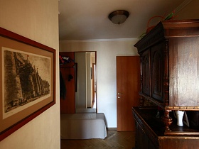 зеркало в стенке, картина на стене напротив деревянного шкафа в прихожей стильной квартиры художника