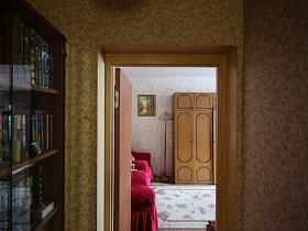 картина на стене, торшер у мебельной стенки, два вишневых мягких кресла в гостиной из открытой двери прихожей квартиры неработающих пенсионеров