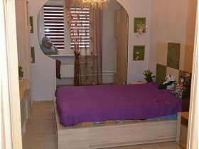 болшая деревянная кровать с фиолетовым покрывалом в детской спальной комнате современной квартиры