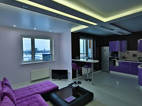 вид со светлой гостиной на фиолетовую яркую кухню с фиолетовой мебельной стенкой современной молодежной двухкомнатной квартиры