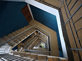 входные двери жилых квартир на лестничной площадке интересной по архитектуре винтовой лестницы в подъезде жилого многоэтажного дома в Москве