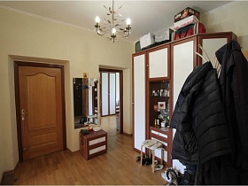 большой коричневый шкаф с белыми дверцами и напольной вешалкой в прихожей простой квартиры на Садовом