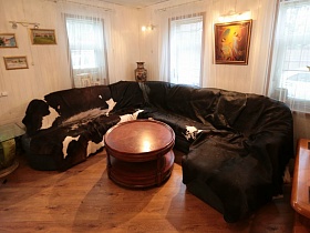 круглый журнальный стол у большого  углового дивана в просторной светлой гостиной современной классической дачи
