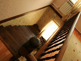деревянная лестница с резными перилами с высоты второго этажа пустого съемного дома в сосновом лесу