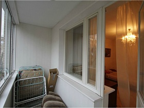 открытая дверь из гостиной на застекленный балкон с белыми стенами съемной трехкомнатной квартиры с ресепшн