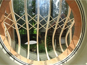 круглое окно-иллюминатор с белой решеткой в двухэтажном современном доме для съемок кино