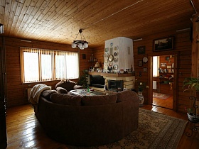 камин и мягкая серая мебель вокруг журнального столика на цветном ковре в гостиной уютной деревянной загородной двухэтажной дачи