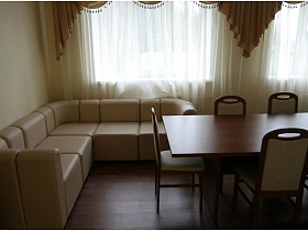 белый угловой мягкий диван у окна в комнате отдыха
