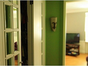 маска на зеленой стене в прихожей однокомнатной квартиры в жилом доме