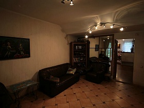 картина над стеклянным журнальным столиком, мягкая мебель, книжный шкаф в кремовой гостиной классической семейной двухэтажной дачи
