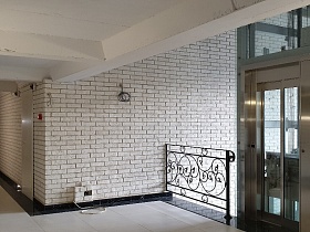 белый потолок и стены из белого кирпича в современном подъезде с лофт стекло колодцем в стиле хай тэк