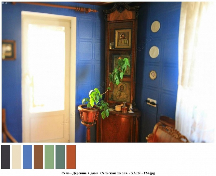 комнатный цветок на деревянной подставке, иконы на полках углового деревянного шкафа в голубой комнате сельского дома