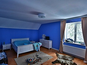 настольная игра на темном столе, белая кровать с синим одеялом, коллаж с фотографиями и телевизор на белой тумбе в детской голубой спальне современого кирпичного дома