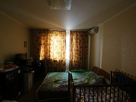 зашторенное окно коричневыми цветными шторами в спальной комнате обычной квартиры в новостройке