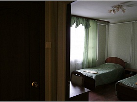 светло зеленые шторы и стеганные покрывала на кровати в номере