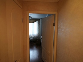 открытая дверь в гостиную из бежевого коридора в семейной трешке