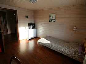черный пакет на белом комоде в углу спальни с деревянной кроватью , покрытой леопардовым покрывалом современного деревянного дома